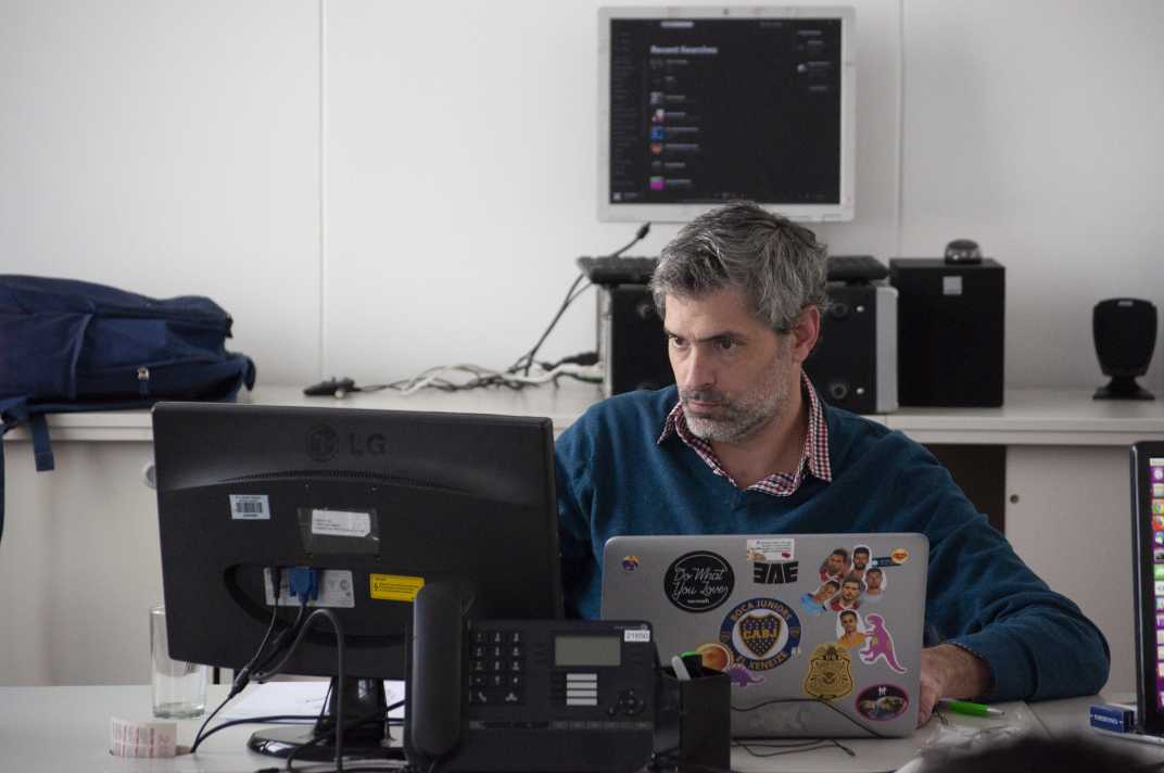 Man using different graphic design outsourcing tools in a laptop and monitors.
